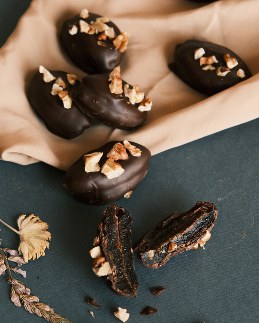 Čokoladni desert bez šećera, šljive u crnoj čokoladi sa komadićima oraha, umetnička kompozicija