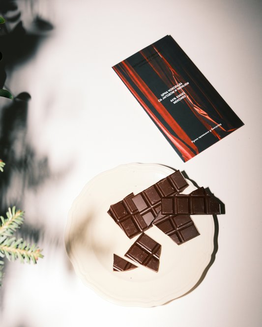 Čokolada sa jagodom i čilijem na tanjiru uz pakovanje Valentina i Karanfil — tamna čokolada bogate teksture i umetničkog dizajna.