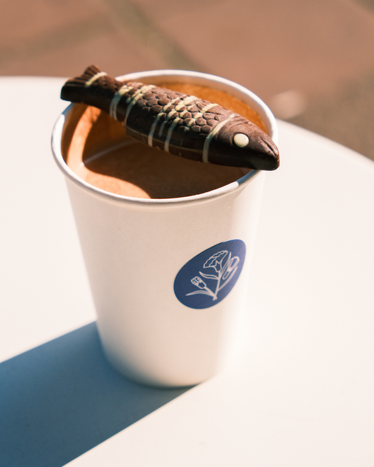 Tropska ribica naslonjena na čašu tople čokolade – pralina s pistaćem i malinom.