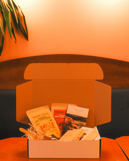 Otvoreni novogodišnji poklon paket sa toplom čokoladom, pralinama i čokoladnim tablama