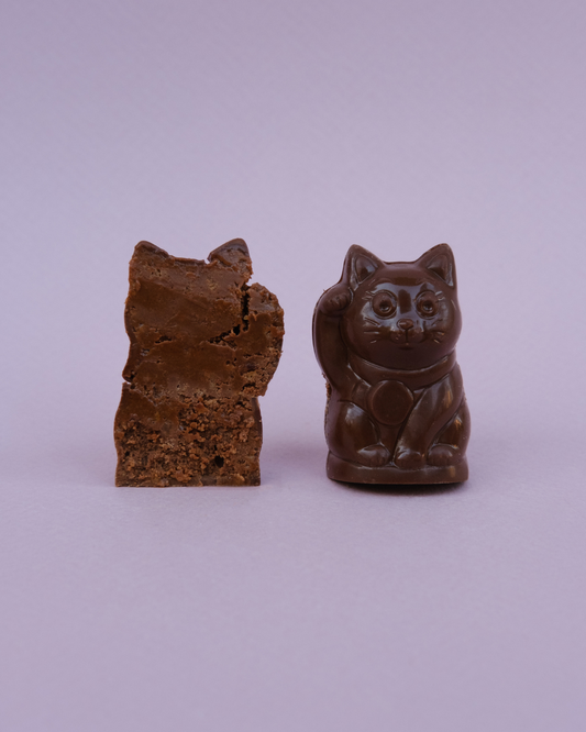 Lucky Cat pralina – cela i presek; vidljiva kremasta punjenja od pekan paste i sloj hrskavog francuskog keksa.