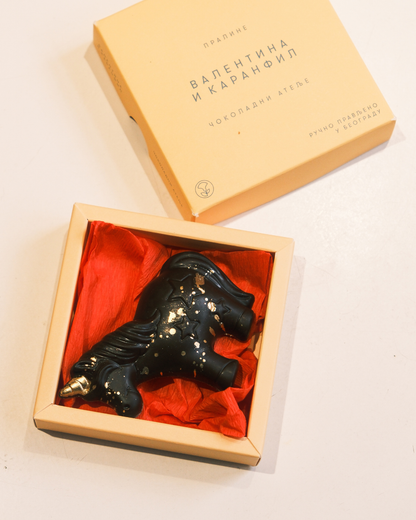 Čokoladni Jednorog od crne čokolade sa jagodom i kikiriki puterom, u elegantnoj poklon kutiji sa crvenim papirom.