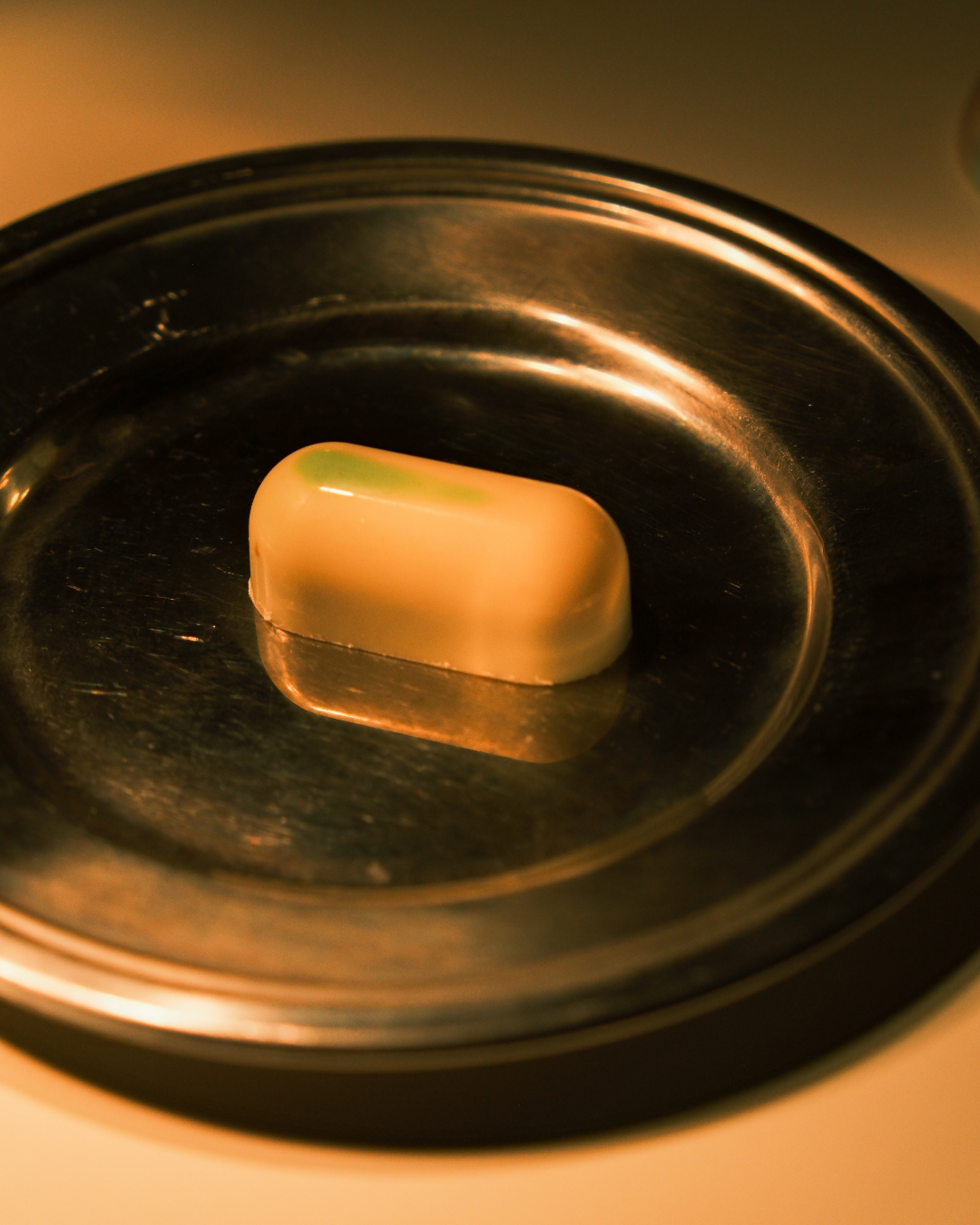 Pralina od bele čokolade sa matchom i marakujom na tamnom tanjiru, ručno pravljena, Valentina i Karanfil.