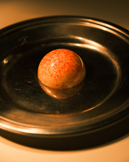 Pralina u beloj čokoladi sa ružičastim tufnama na metalnom tanjiru – ukus kokos, jagoda i Malibu rum