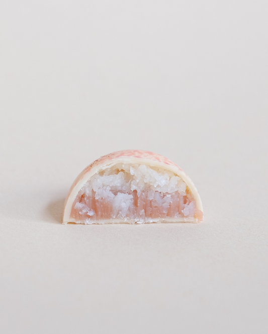 Grupica sjajnih kupolastih pralina od bele čokolade sa roze pegicama – kokos i jagoda