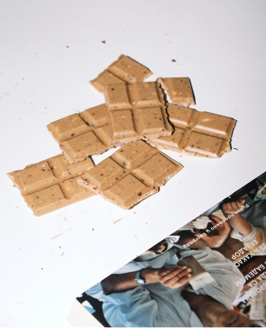 Kockice bele karamelizovane čokolade sa bademima uz ambalažu Valentina i Karanfil — detalj teksture i boje čokolade.