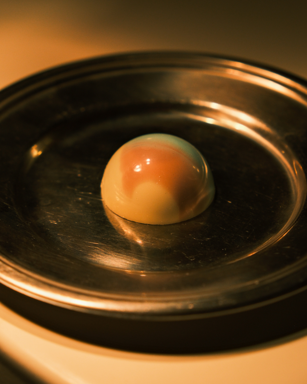 Bela čokoladna pralina sa lavandom i zovom na srebrnom tanjiru, ručno pravljena.