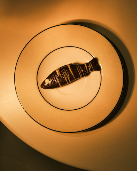 Tropska ribica – pralina od tamne čokolade 60% sa dekorom, na tanjiru.