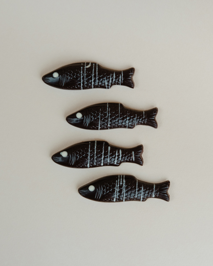 Četiri čokoladne ribice od tamne čokolade sa belim dekorom, ravnan raspored