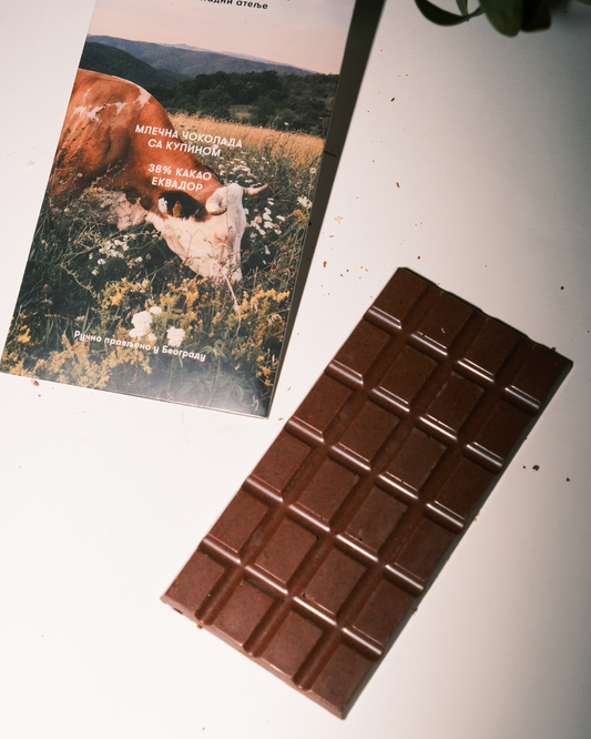 Tabla mlečne čokolade sa kupinom uz pakovanje Valentina i Karanfil, minimalistična fotografija na beloj pozadini.