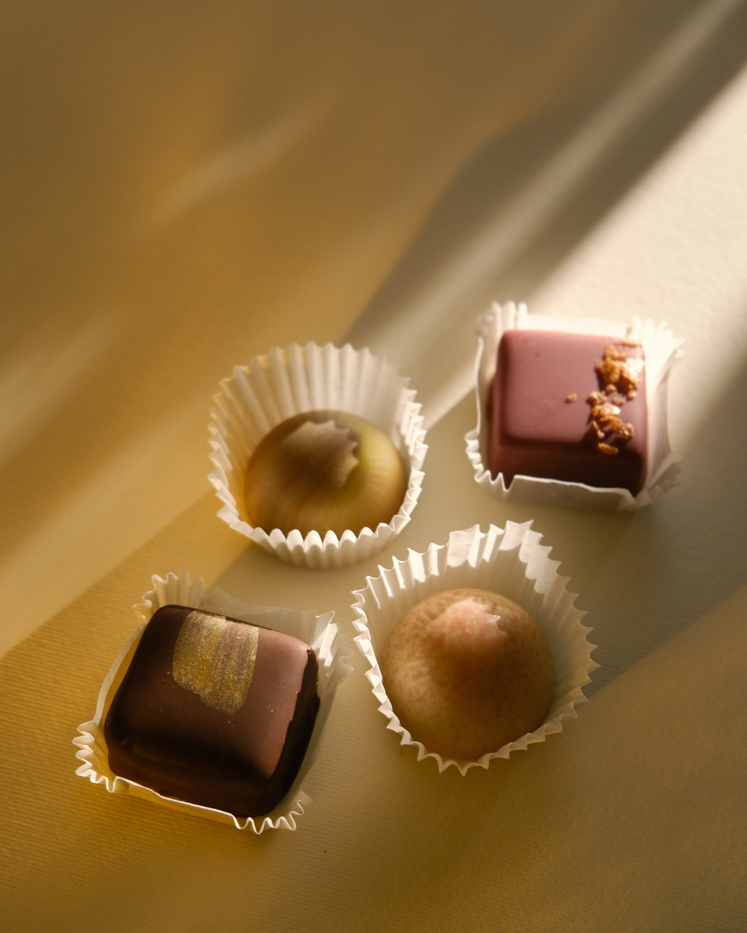 Ručno rađene praline Valentina i Karanfil u prirodnom svetlu – savršen balans umetnosti i ukusa.